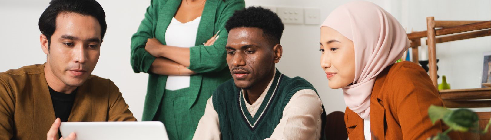 A group of multicultural students working at a laptop